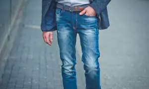 Mężczyzna w niebieskiej marynarce i modnych, przetartych jeansach. Różne rodzaje jeansów męskich można nosić na wiele sposobów.
