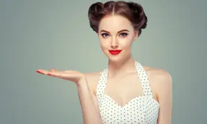 Kobieta w stylu pin-up z burzą loków i czerwoną szminką prezentuje coś na otwartej dłoni.