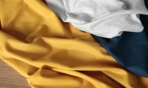Miękki, lejący się rayon materiał w kolorze musztardowym, szarym i granatowym, ułożony w fałdy.