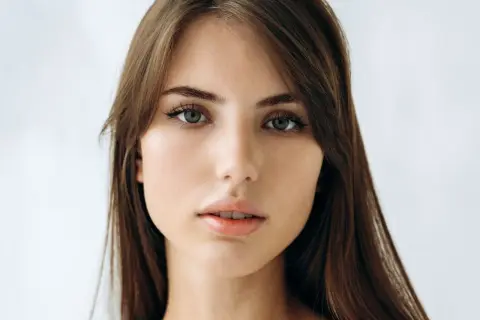 Delikatna, soft girl z zielonymi oczami i brązowymi włosami, patrzy prosto w obiektyw.