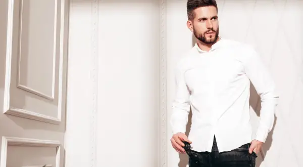Mężczyzna w białej koszuli i jeansach, prezentujący styl slim fit.