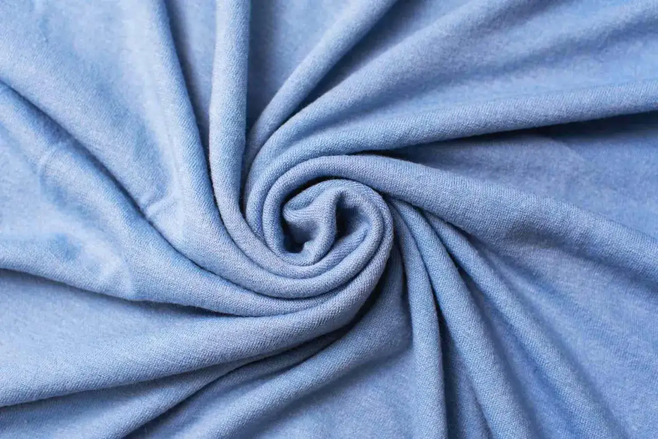 Miękki, błękitny materiał cupro, zwinięty w spiralę. To co to za materiał, który jest tak przyjemny w dotyku?