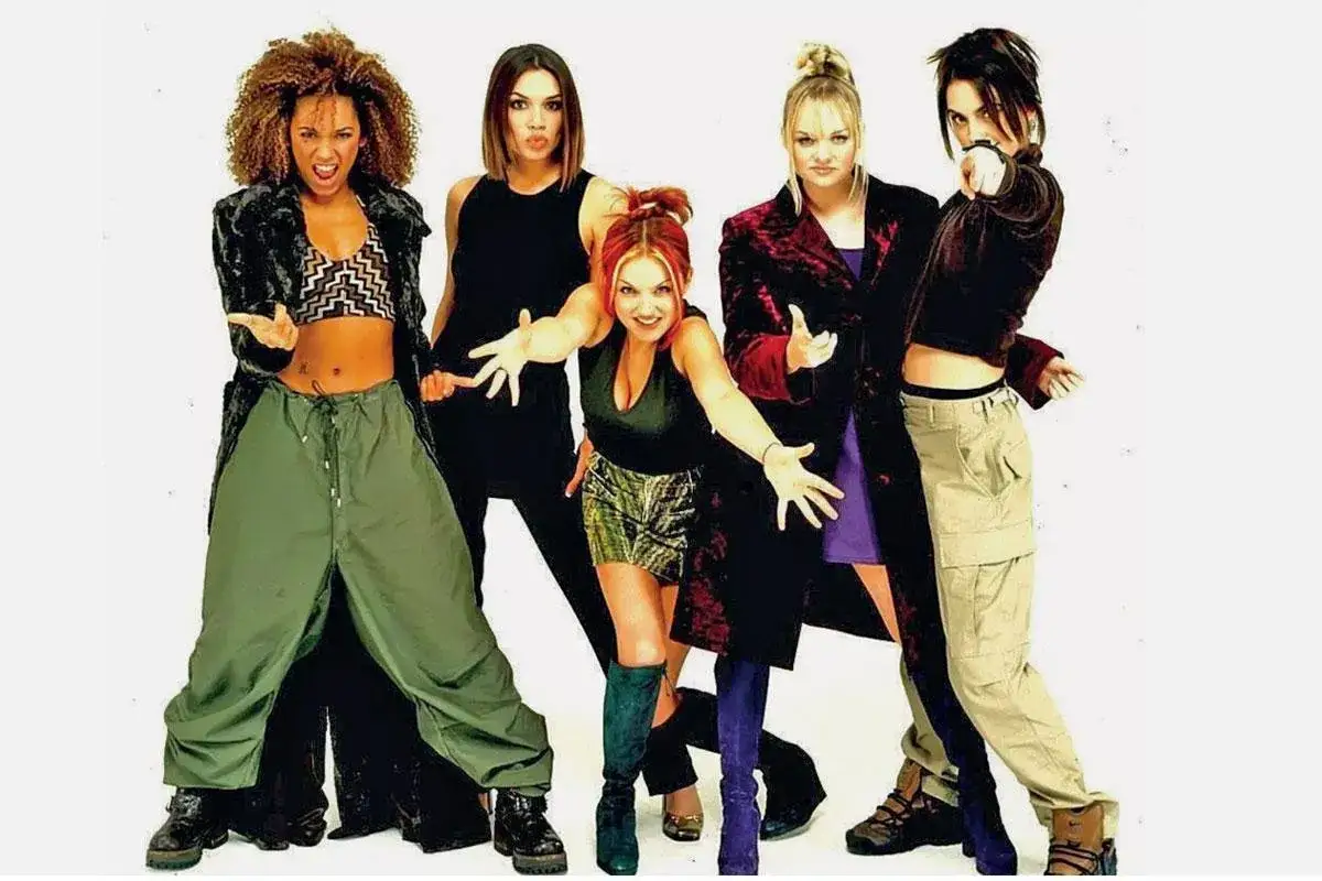Dziewczyny z Spice Girls w stylizacjach y2k: Mel B w bojówkach, Geri w mini, Emma w fioletowej sukience, Posh w aksamicie i Sporty w sportowym stylu.