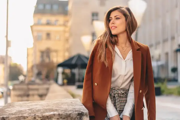 Elegancka kobieta w brązowej marynarce i białej koszuli, w stylizacji z nutą sepia kolor.
