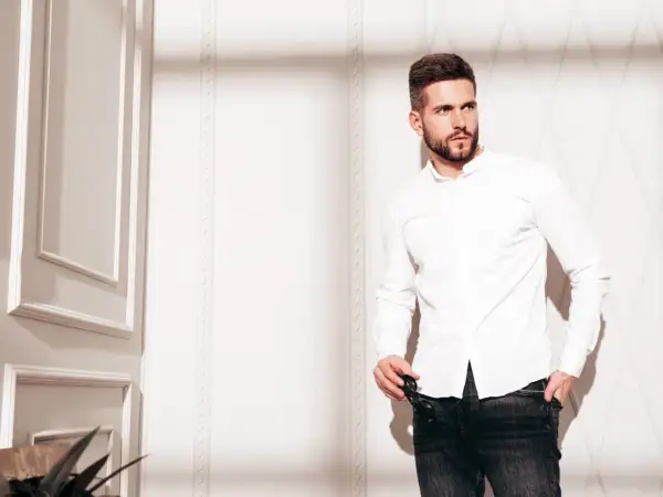 Mężczyzna w białej koszuli i jeansach, prezentujący styl slim fit.