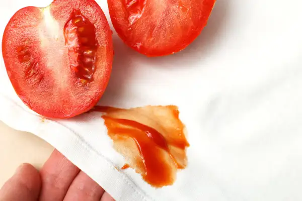 Niefortunny wypadek z pomidorem! Na białej tkaninie pojawiła się wyraźna plama z pomidora, która wymaga natychmiastowego czyszczenia.